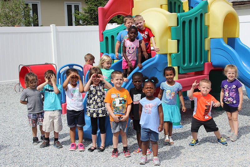 Group of children posing on and in front of a playground structure