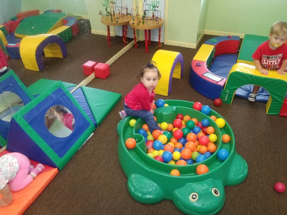Child sitting on the edge of a turtle-shaped ball pit
