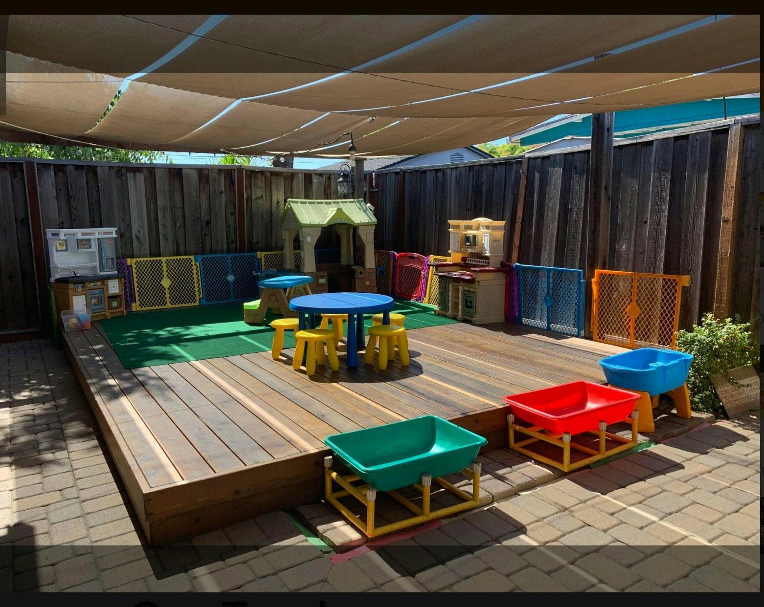Outdoor play area with wooden deck, small table and chairs, and play structures