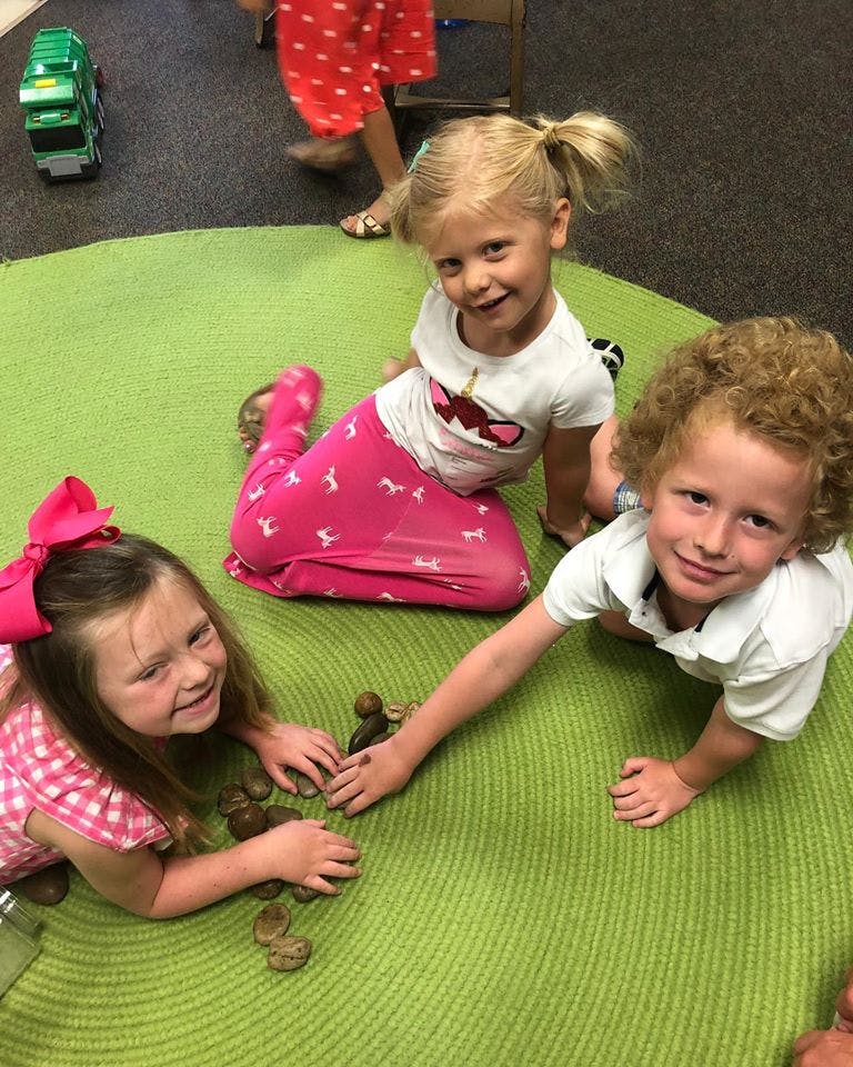 Three children playing on a green rug