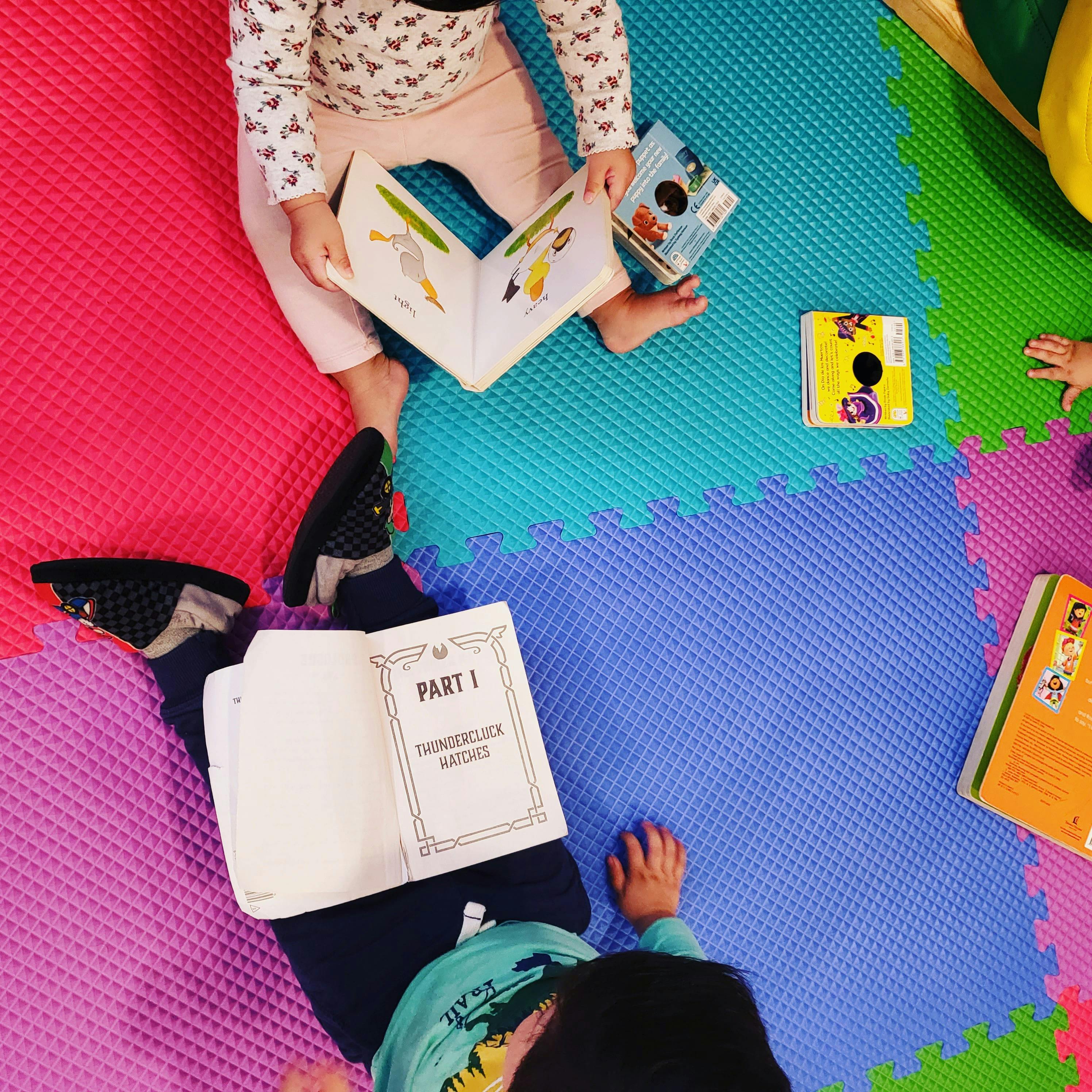Children reading books on a colorful mat
