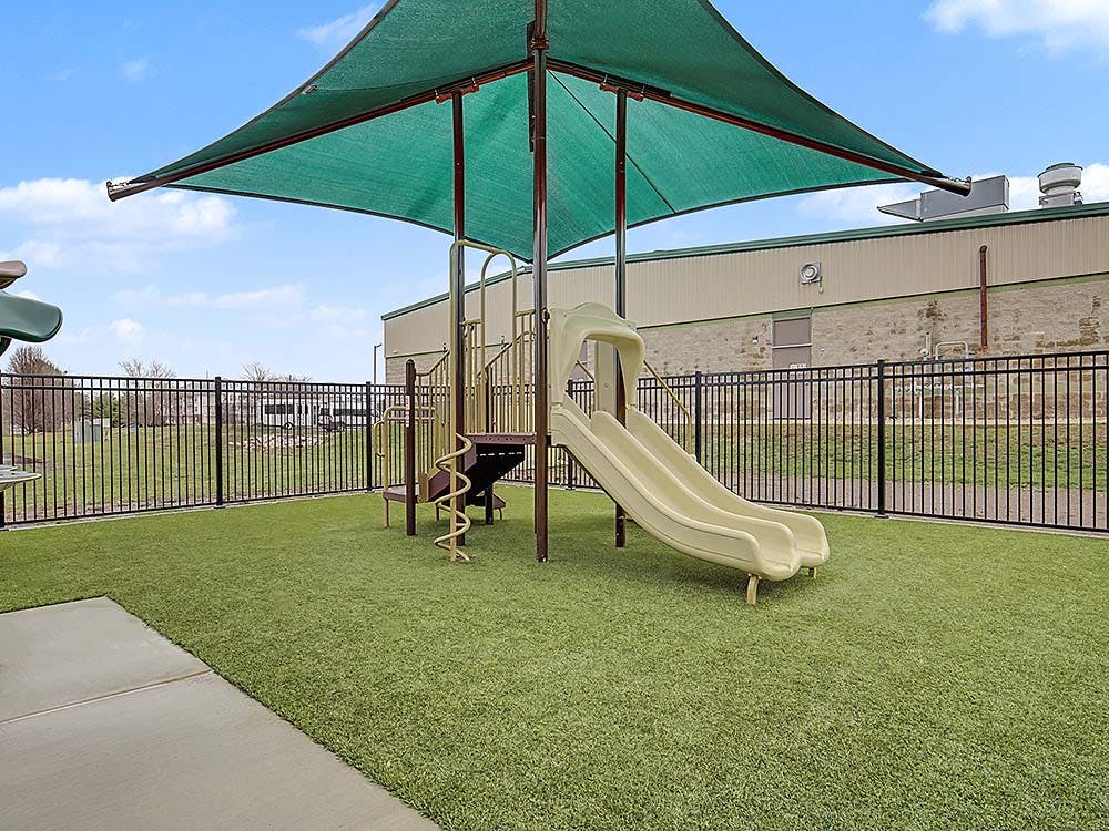 Playground with slides and a climbing structure under a shade cover