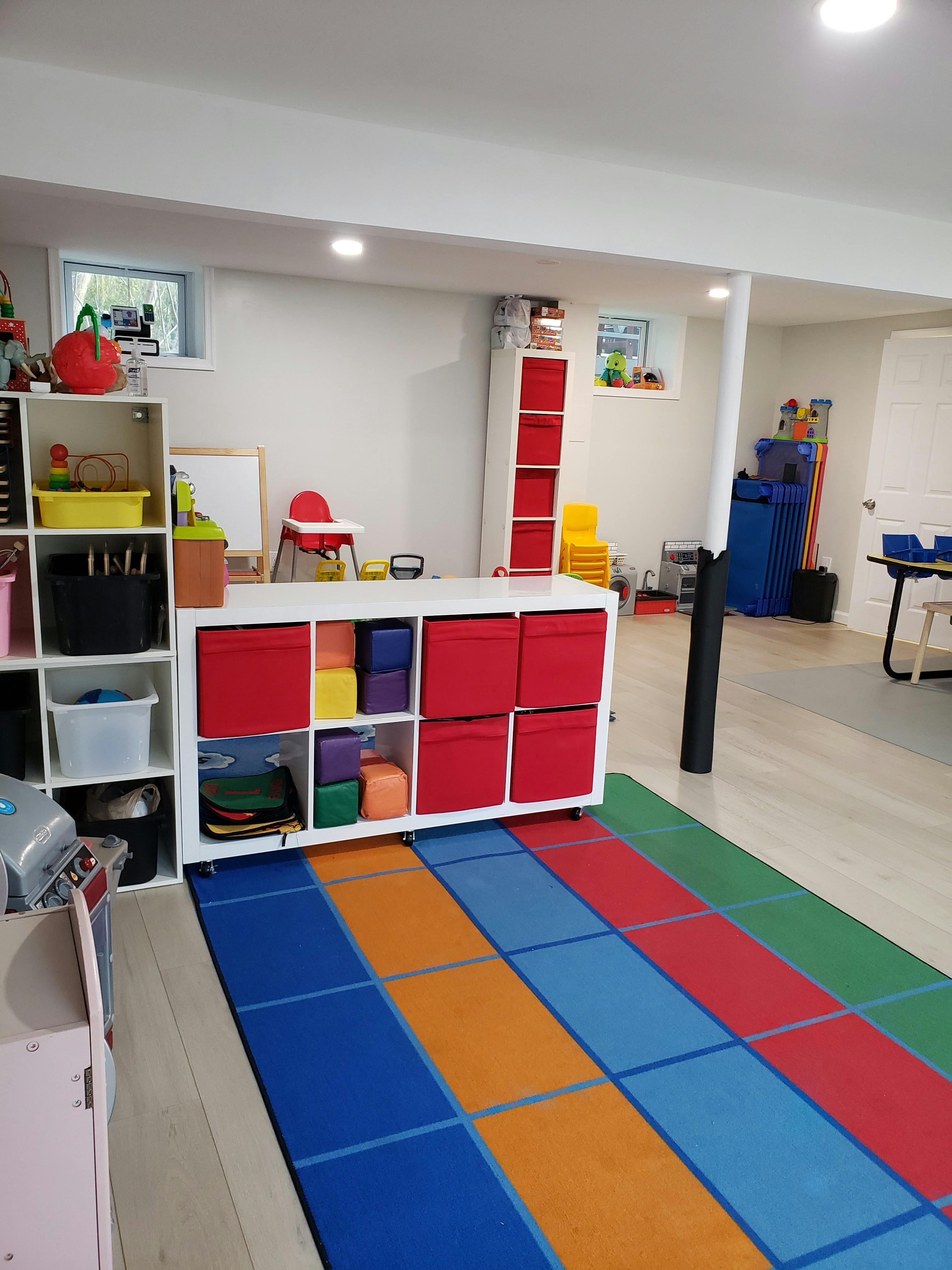Playroom with storage shelves, colorful rug, and child's high chair