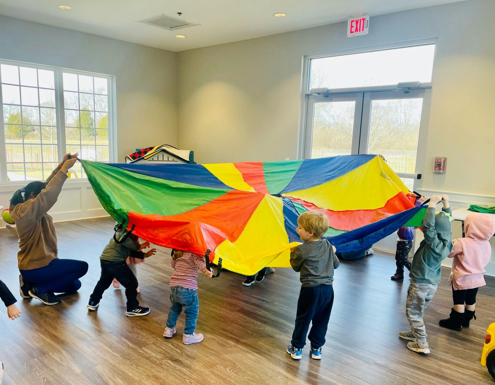 Person and children playing with a colorful parachute