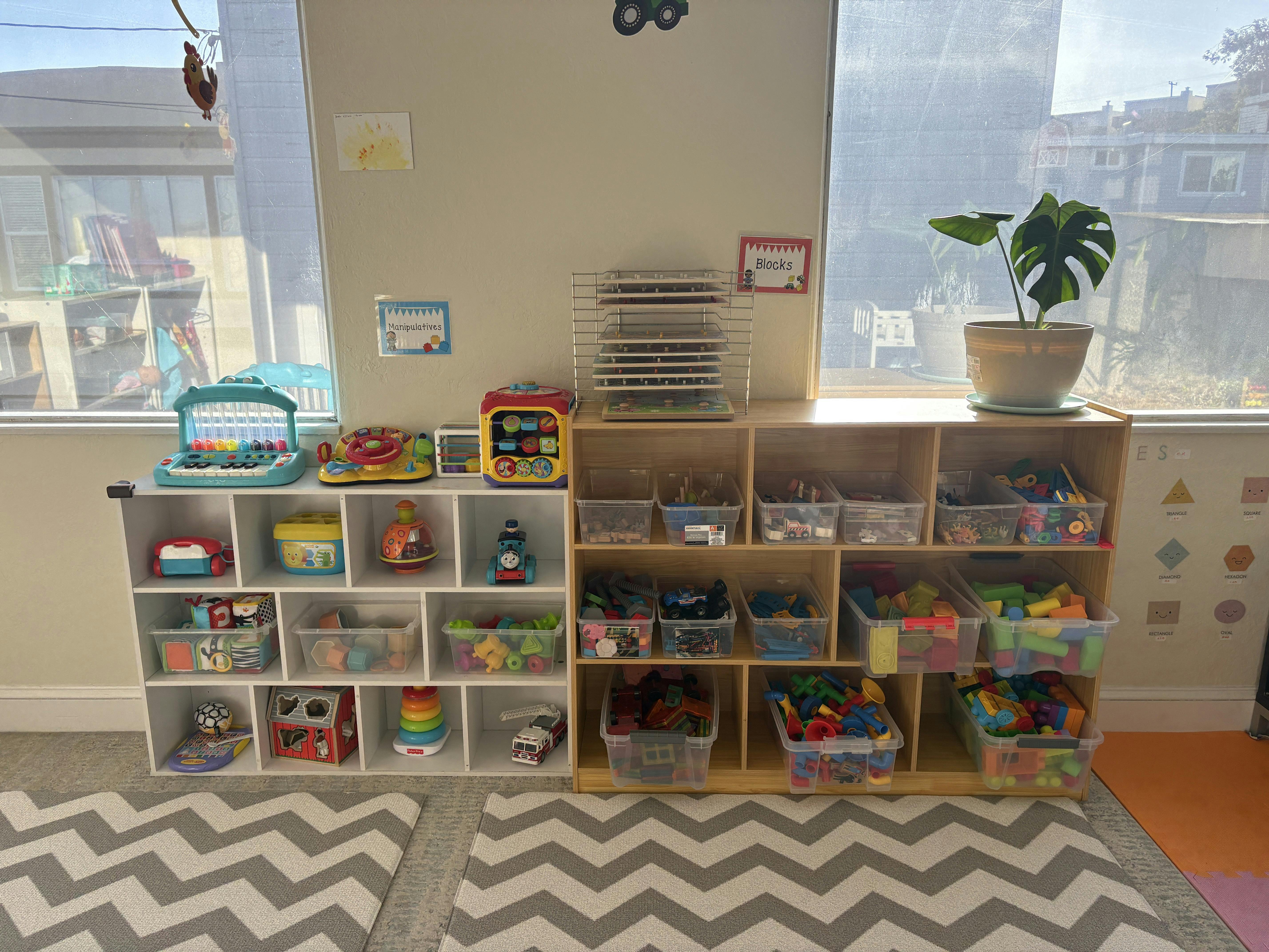 Wooden storage shelves filled with toys and plastic bins in a classroom