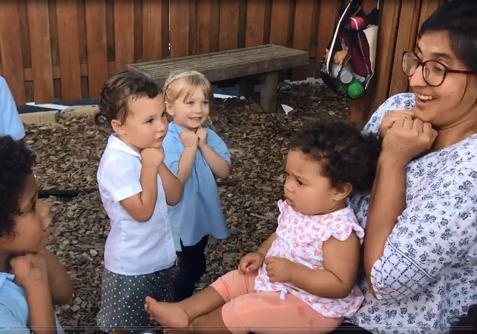 Adult and multiple children sitting and standing outdoors