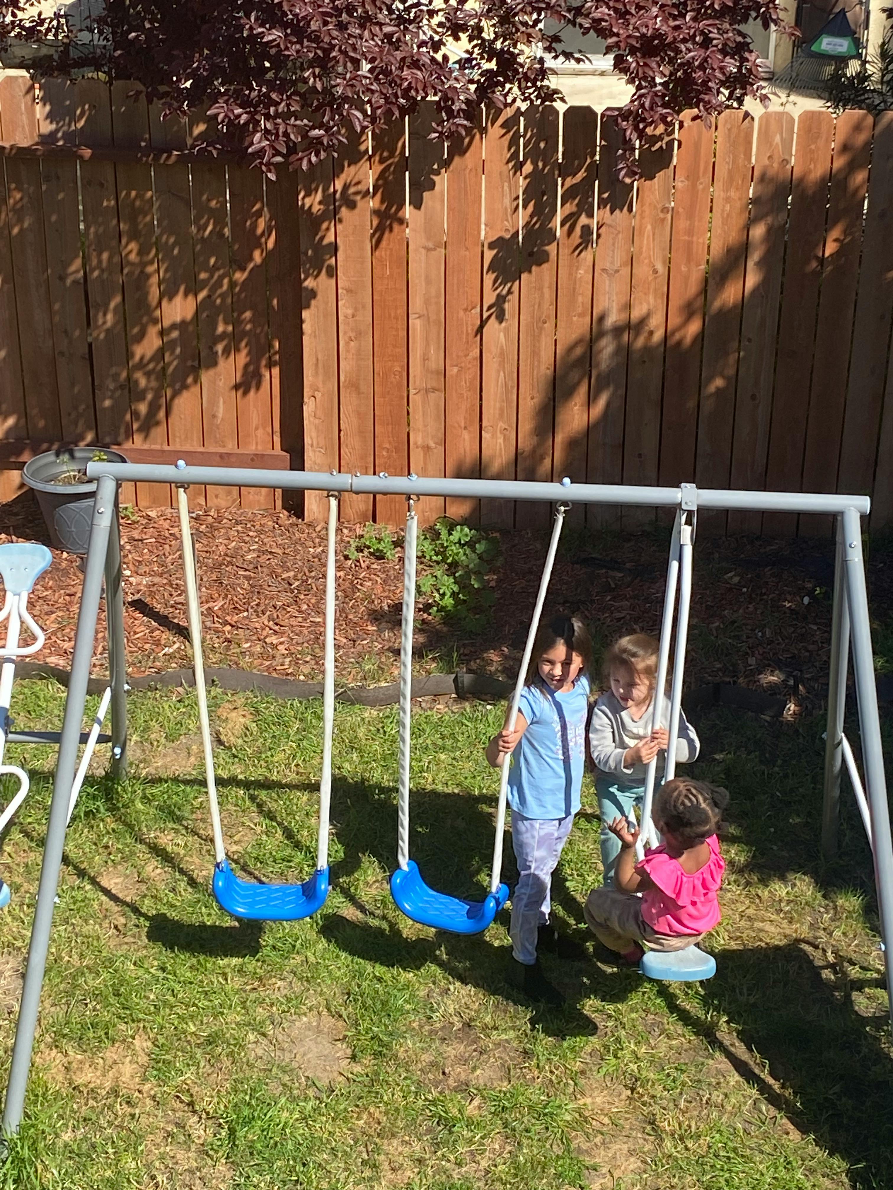 Three children standing by swings on a swing set
