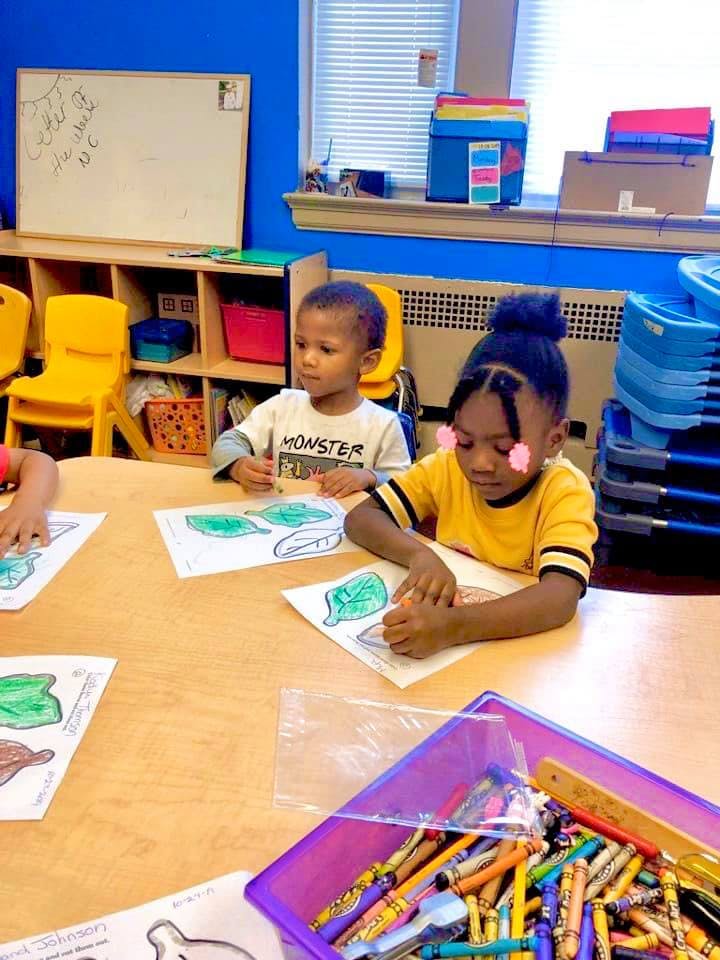 Two children coloring at a table in a classroom