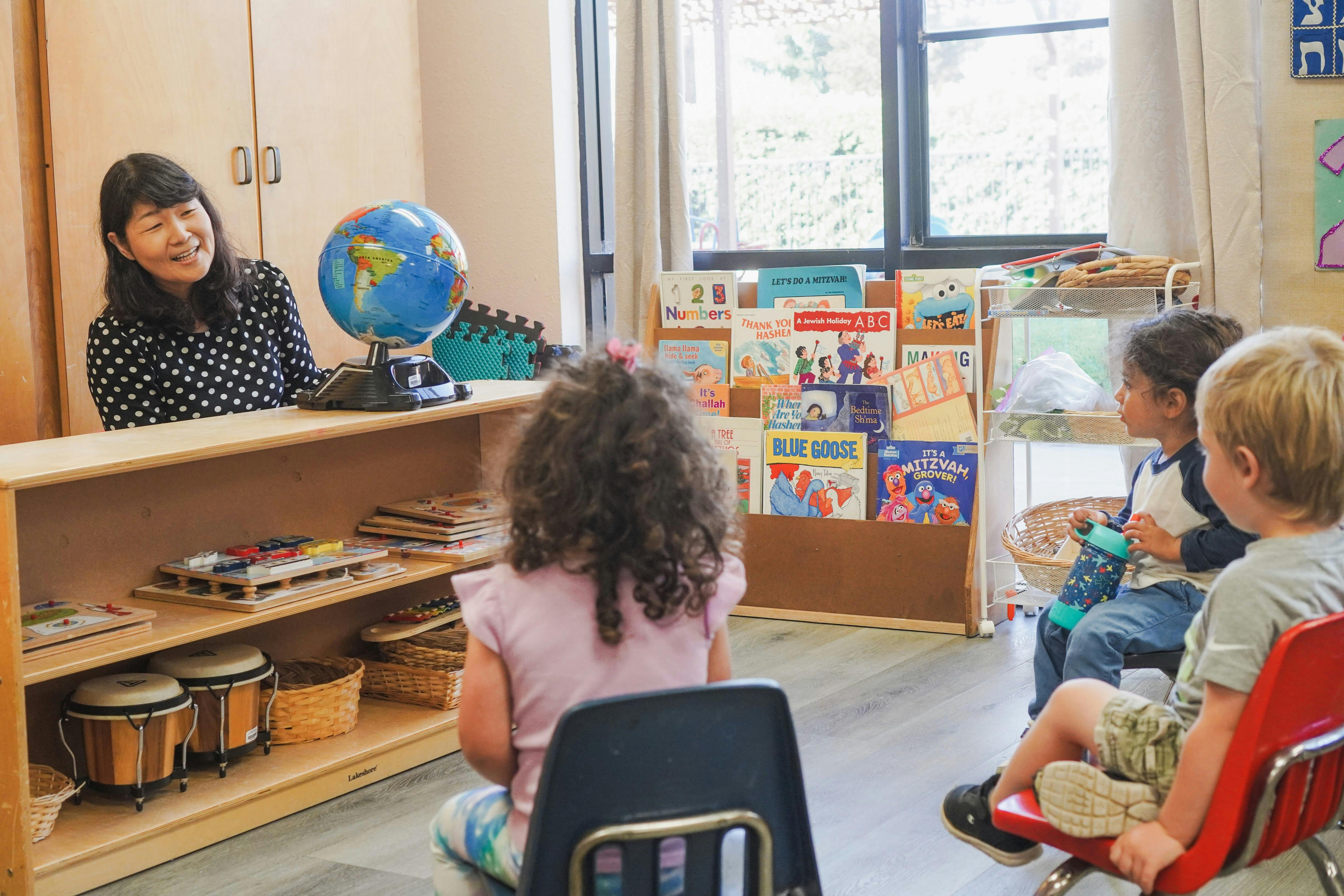 Adult and children in a classroom with a globe on a shelf