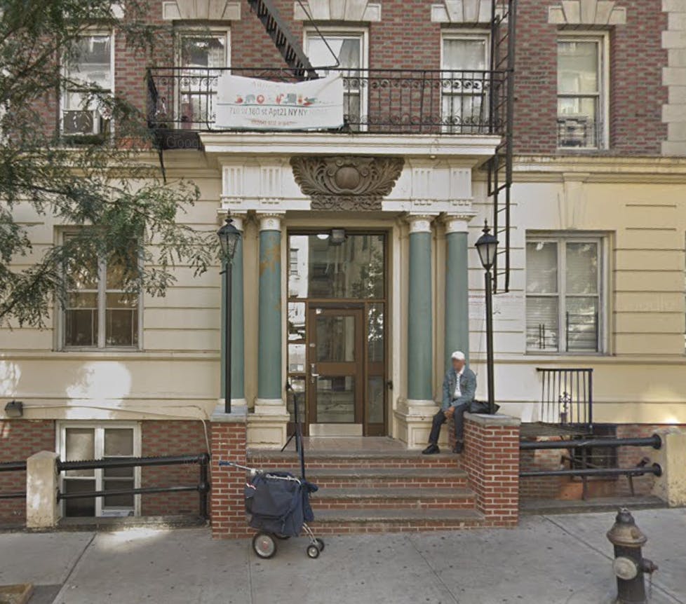 Person sitting on steps of a building entrance with a banner above the entrance
