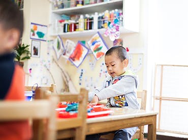 Child playing with toys at a table in a classroom