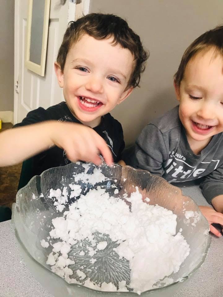 Two children playing with white powder in a bowl