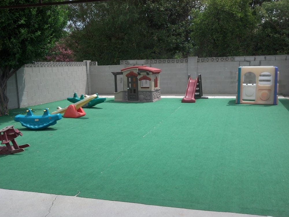Outdoor playground with playhouses, slides, and spring riders on green turf