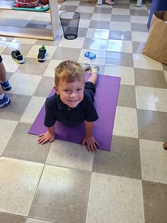Child on a purple mat in a yoga pose