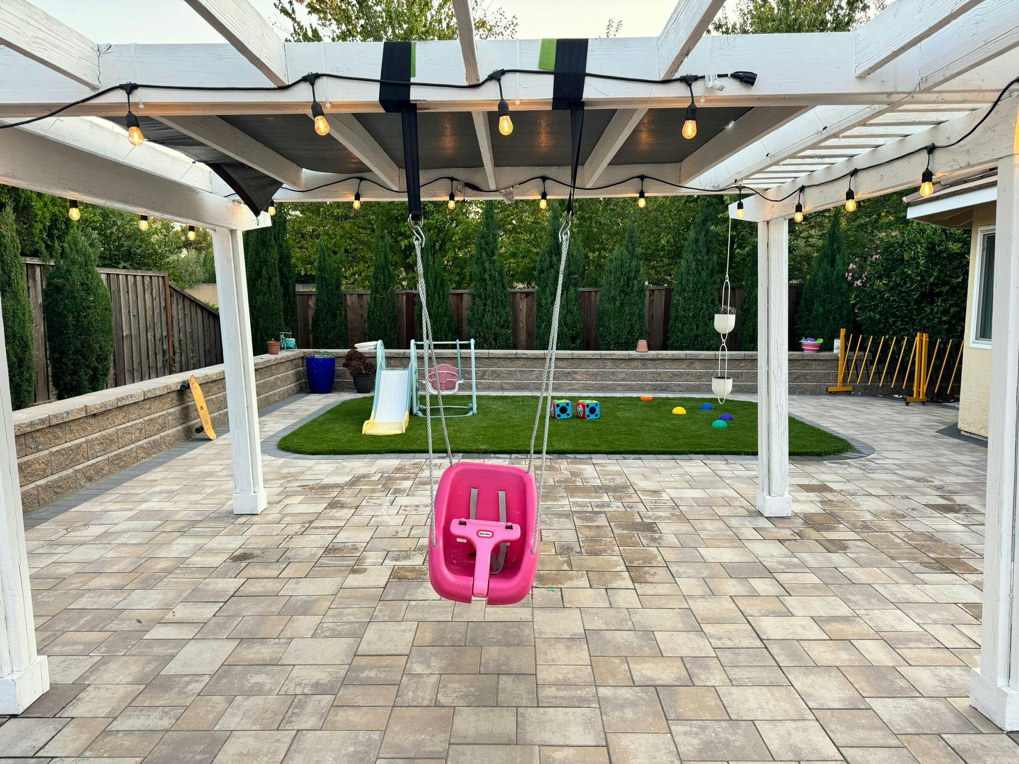 Outdoor patio with a swing set and artificial grass play area