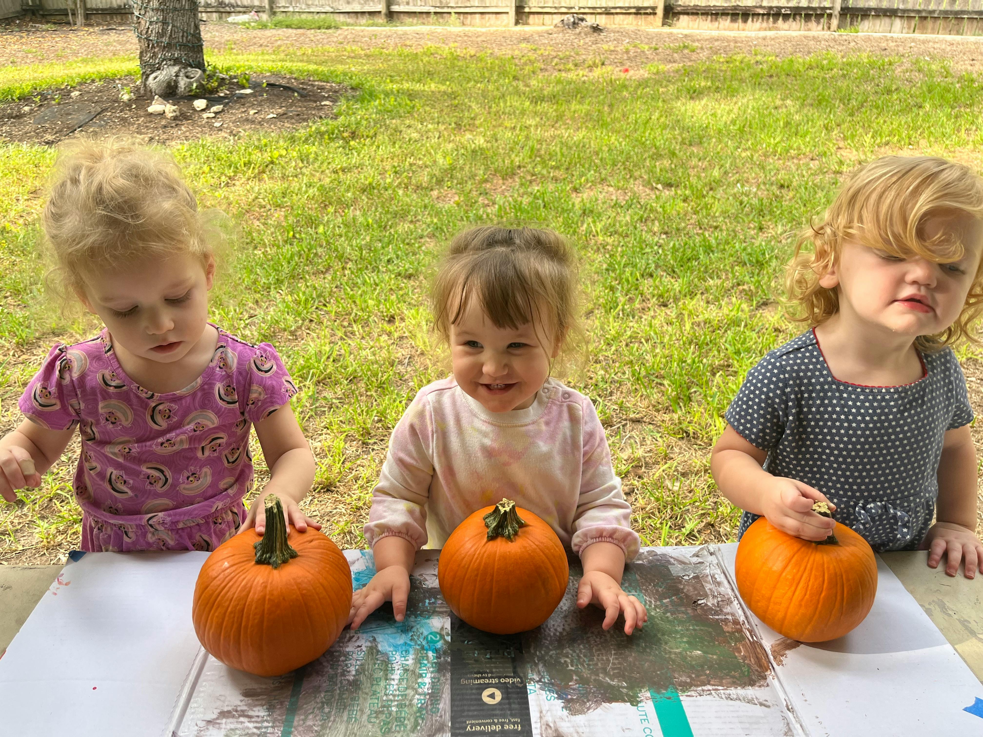 Three children with pumpkins outdoors