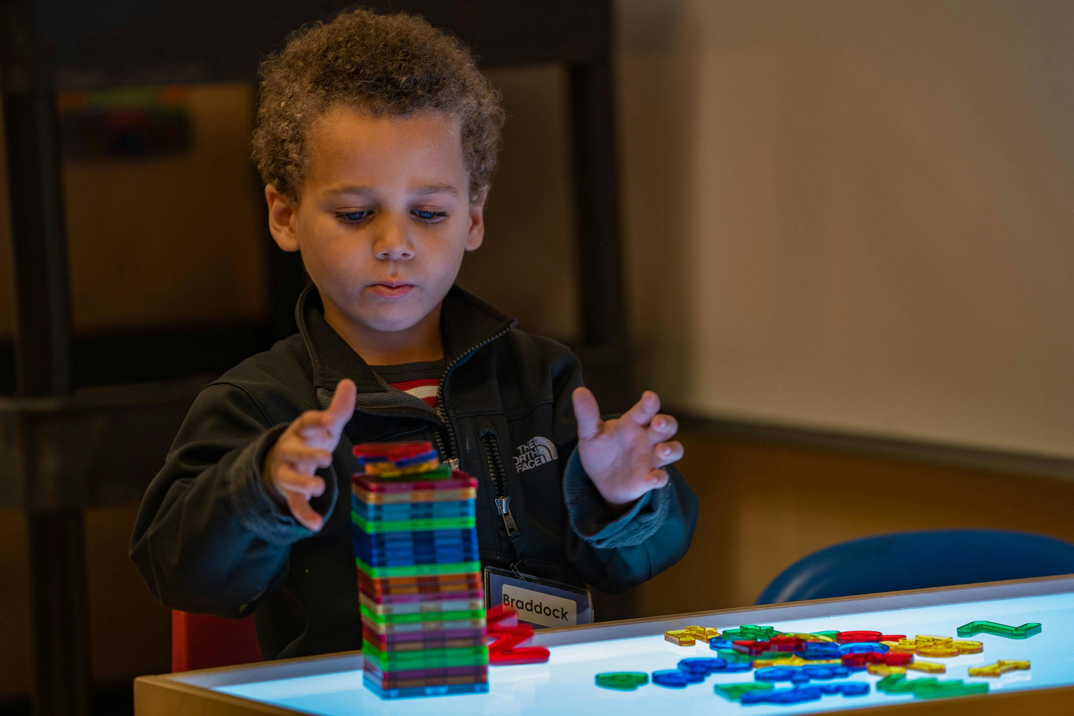 Child playing with colorful magnetic blocks on a light table