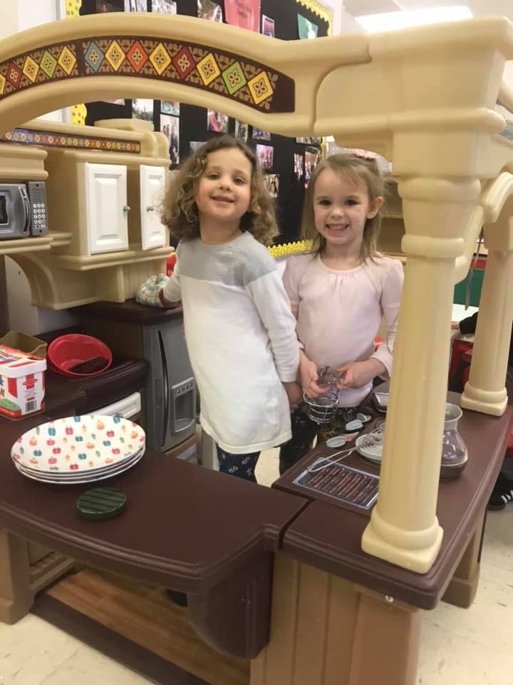 Two children standing in a play kitchen
