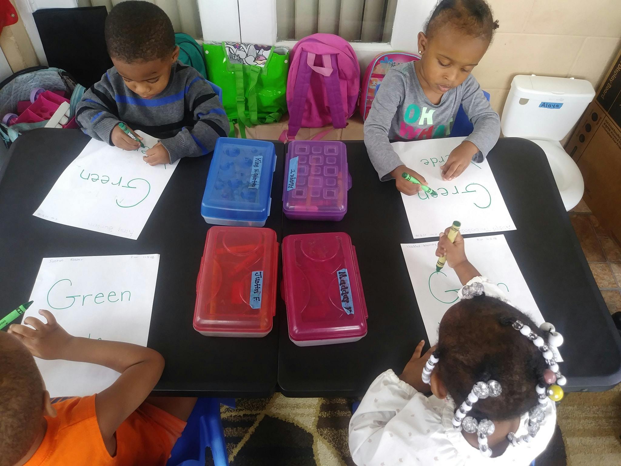 Four children drawing on paper at a table