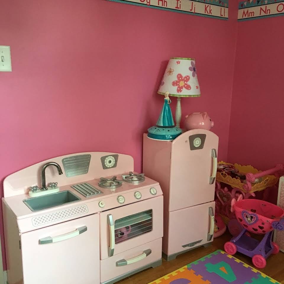 Pink toy kitchen set with stove, sink, and refrigerator