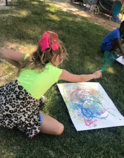 Child drawing on paper on grass