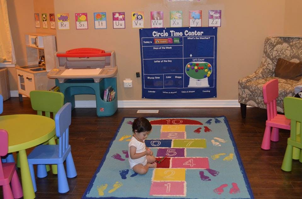 Child sitting on a hopscotch rug in a classroom