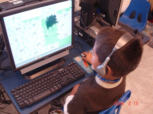 Child wearing headphones using a computer mouse