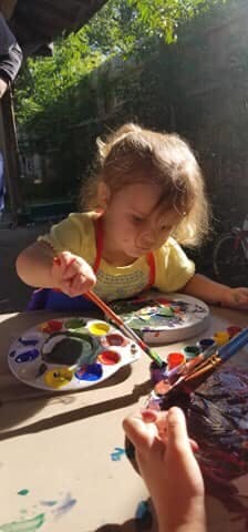 Child painting with a brush and paint palette