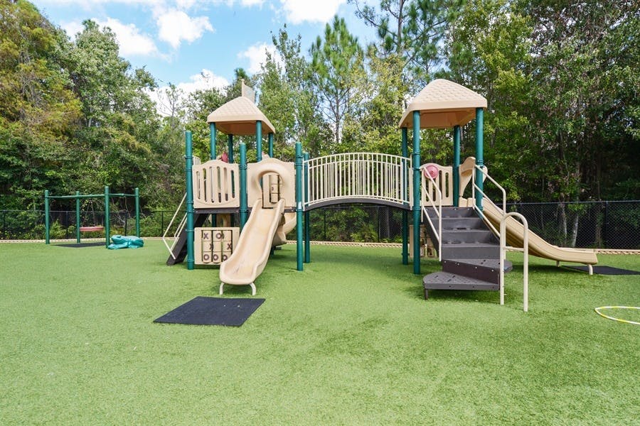 Outdoor playground with slides, stairs, and a bridge on artificial turf