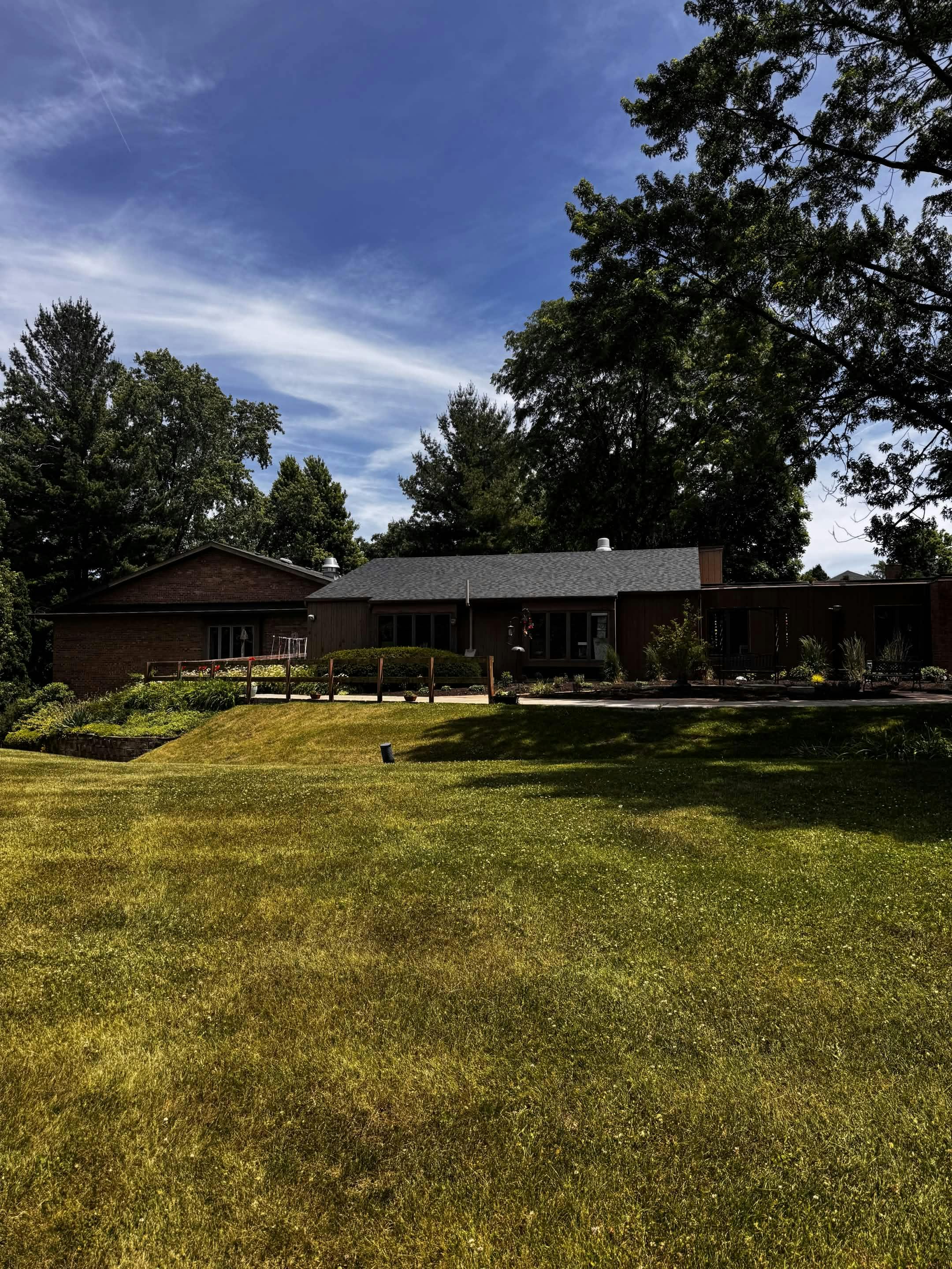 A long, single-story building with a front porch, surrounded by lush green trees