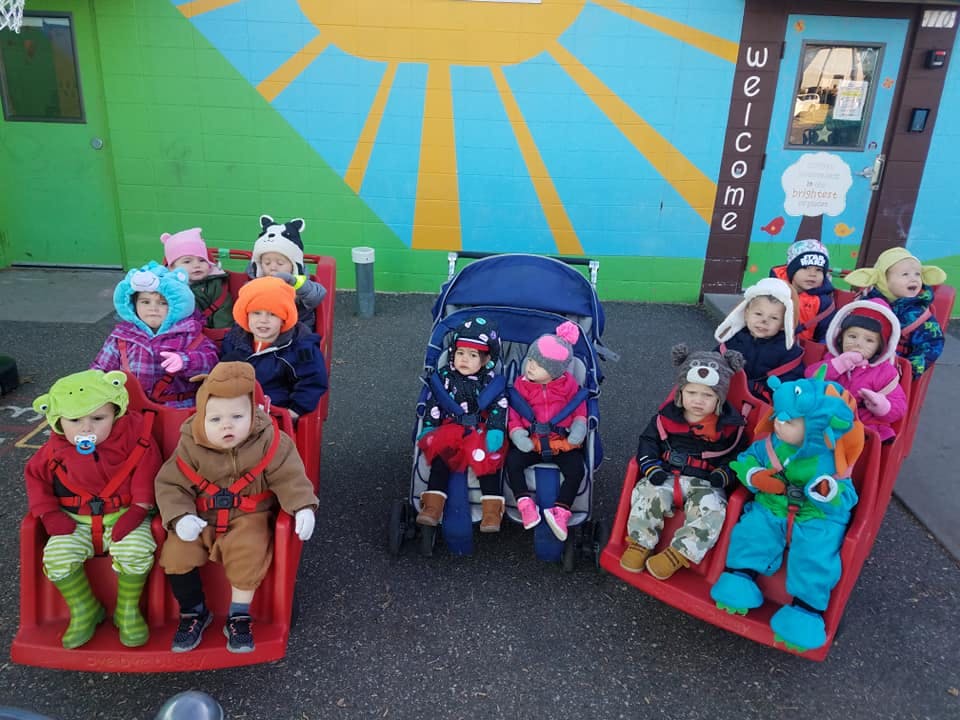 Group of children and babies in winter clothing sitting in sleds and strollers