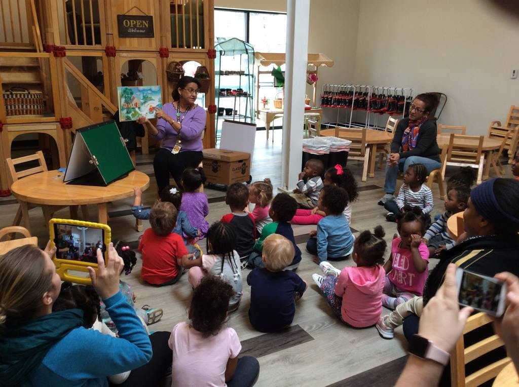 Person reading a book to a group of children in a classroom