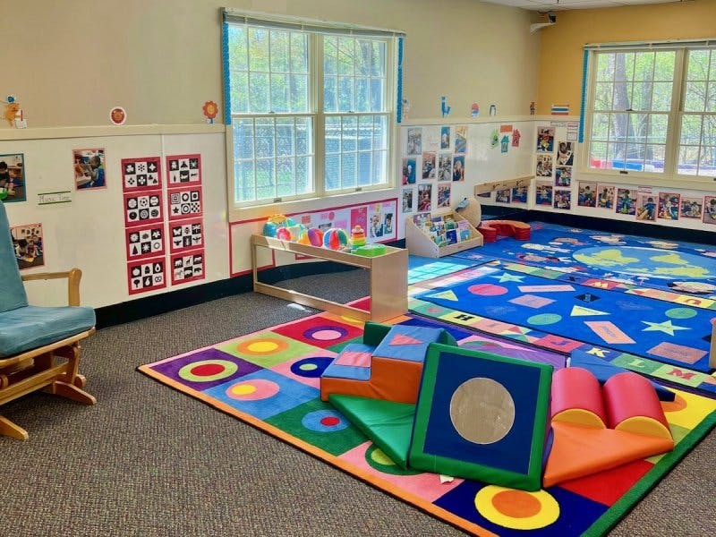 Colorful playroom with soft play equipment, rugs, and windows