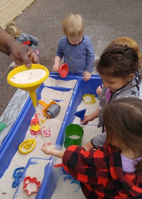 Children playing in a sand and water table with toys