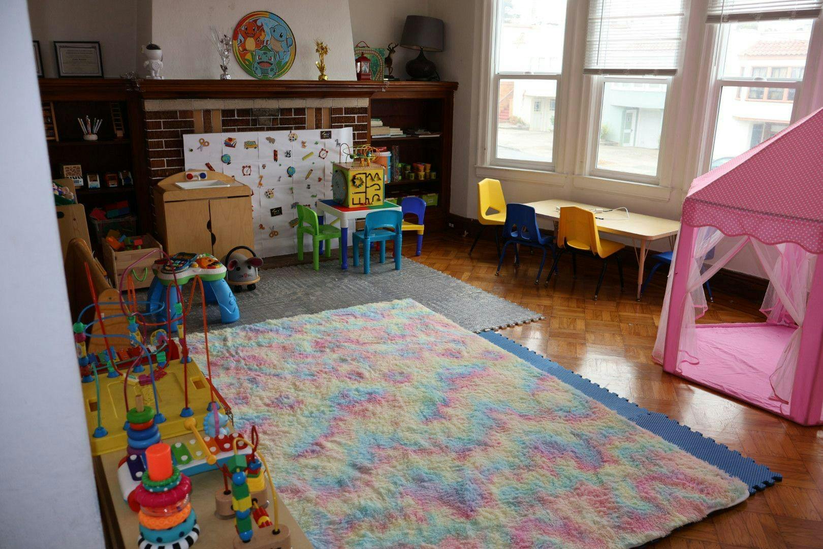 Playroom with colorful rug, small tables and chairs, and a pink play tent