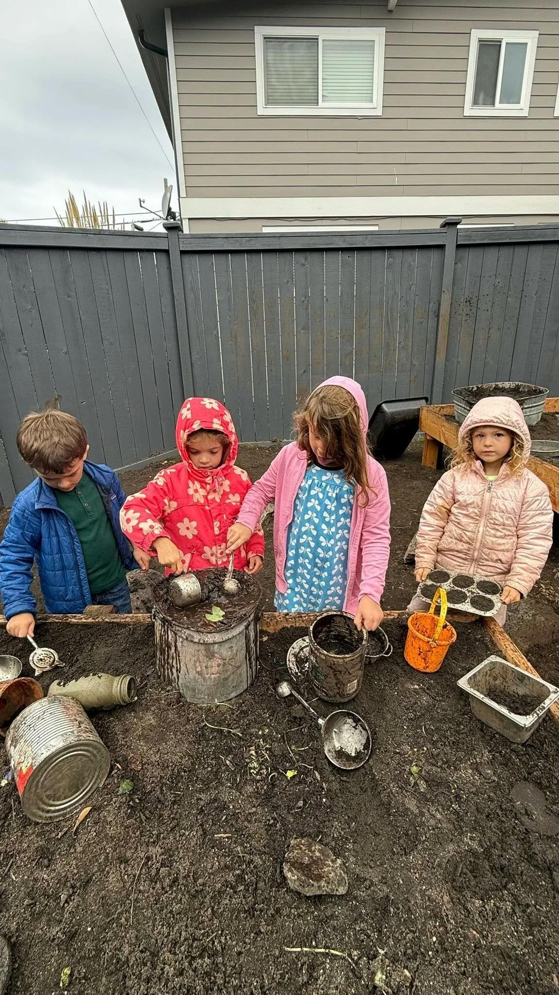 Four children playing in a mud kitchen