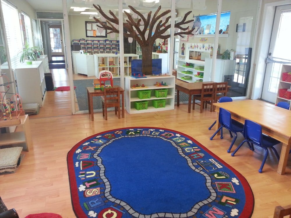 Preschool classroom with a blue rug, tables, and shelves