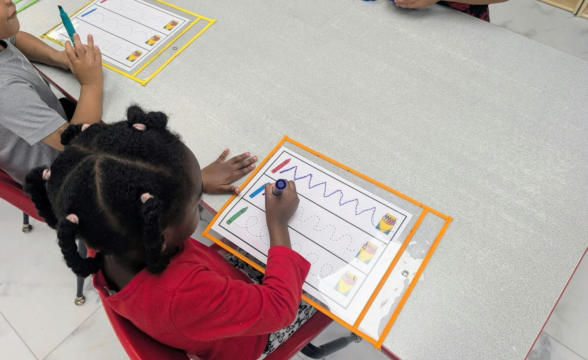 Child tracing lines on a worksheet at a table