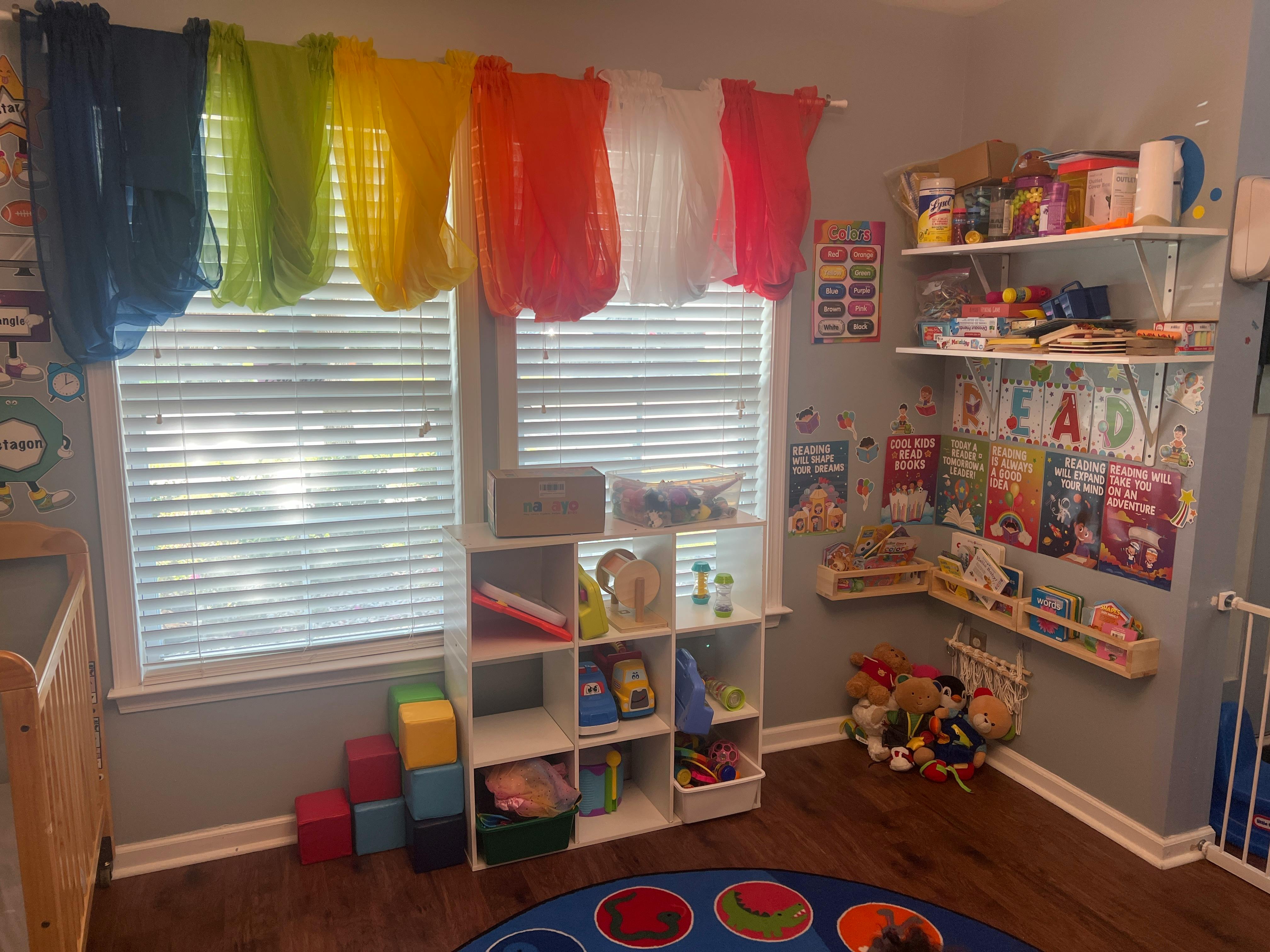 Playroom with colorful curtains, shelves of toys and books, and a round rug