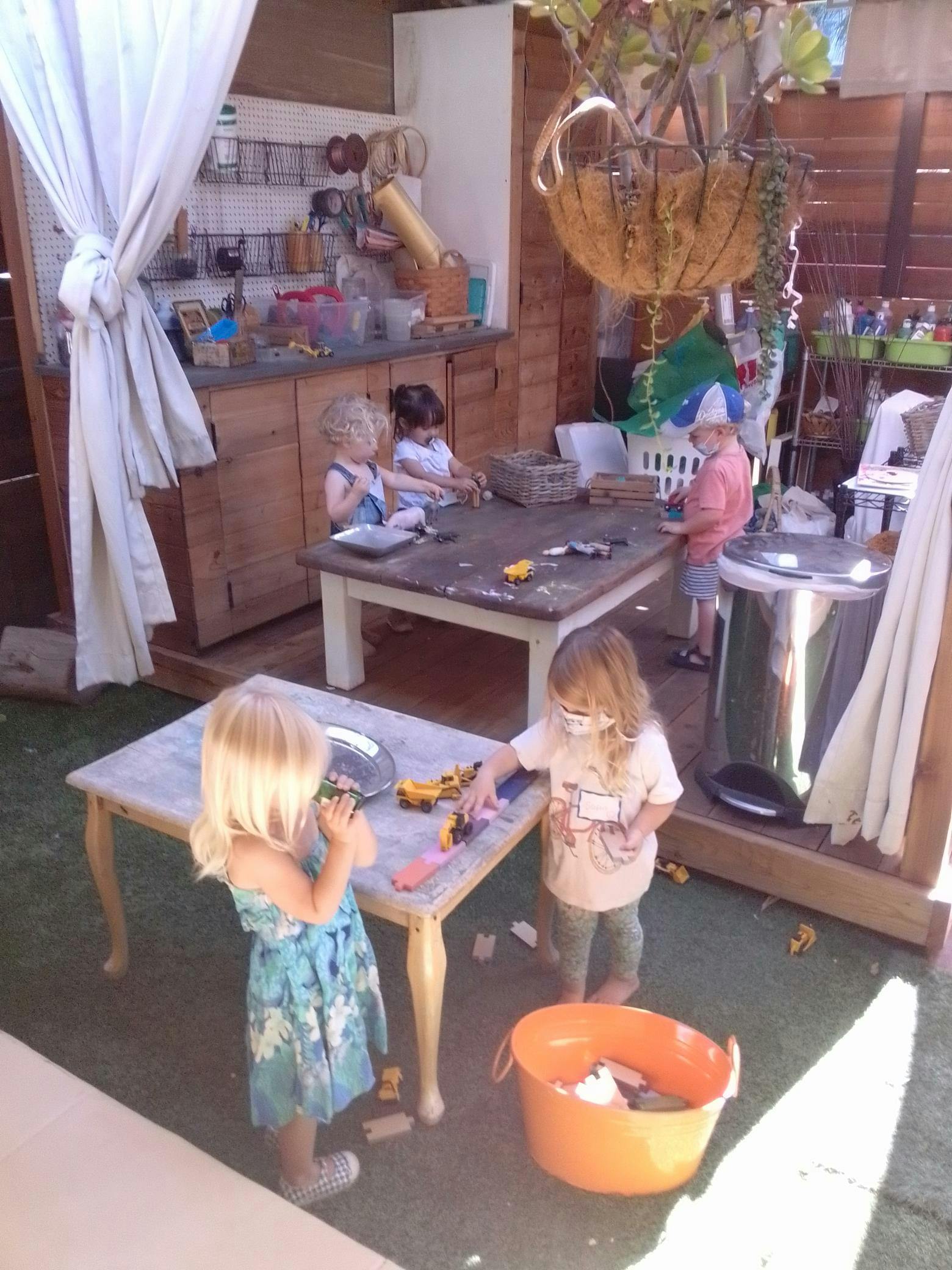 Children playing with toys at tables in an outdoor area