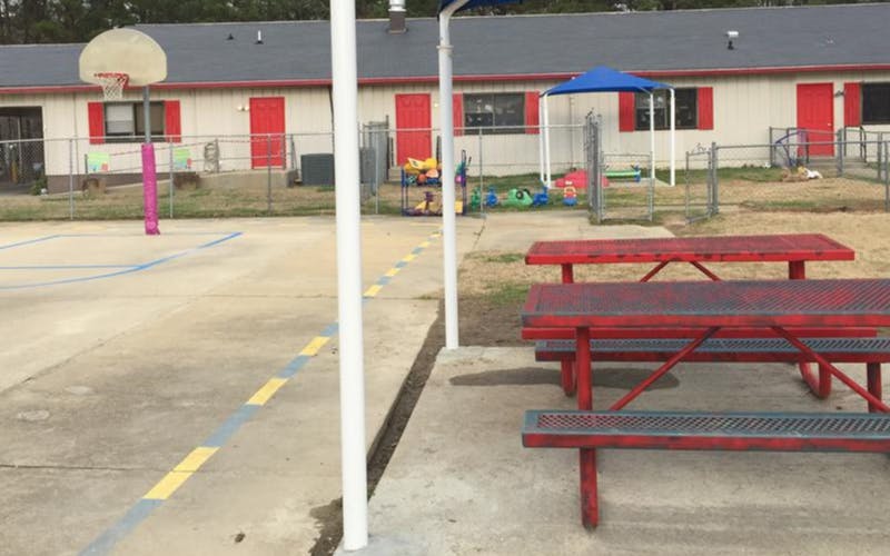 Basketball hoop on a paved court with red picnic tables