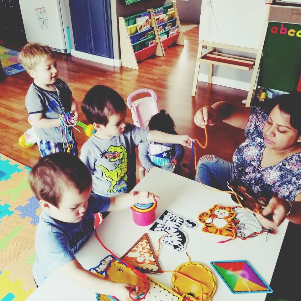 Adult and children playing with lacing toys at a table