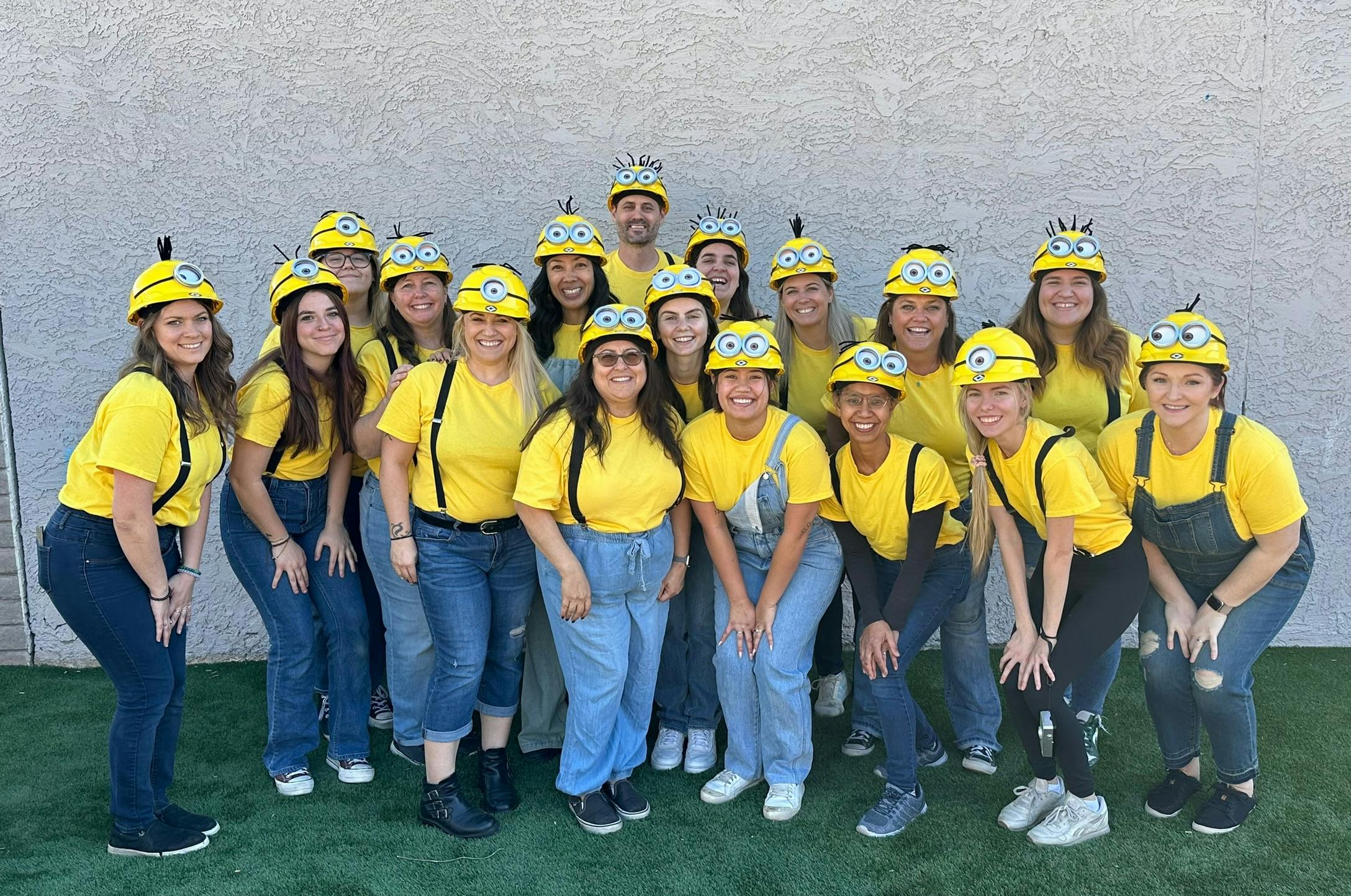 Group of people in yellow shirts, blue overalls, and Minion-themed hats