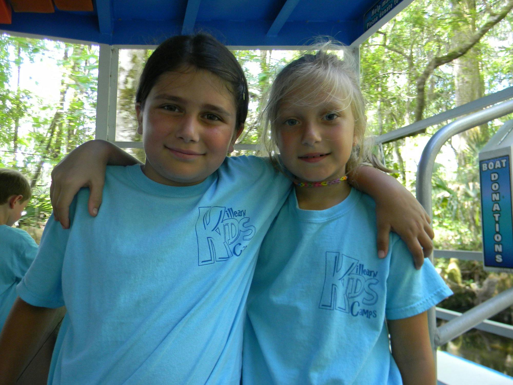 Two children in light blue shirts with arms around each other