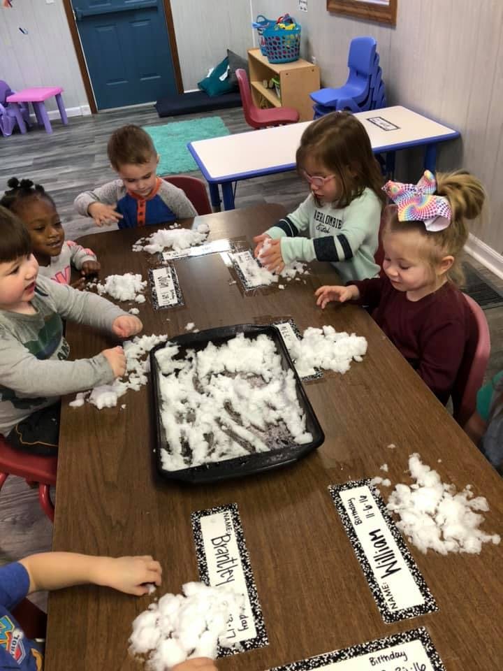 Children playing with artificial snow at a table