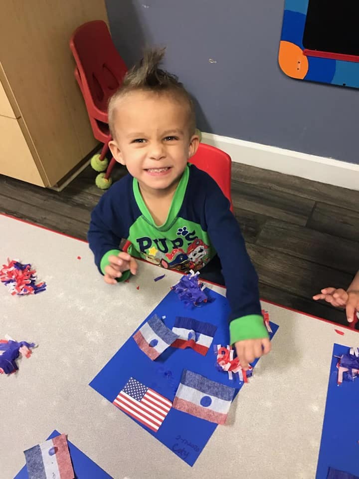 Child sitting at a table with flags and craft supplies