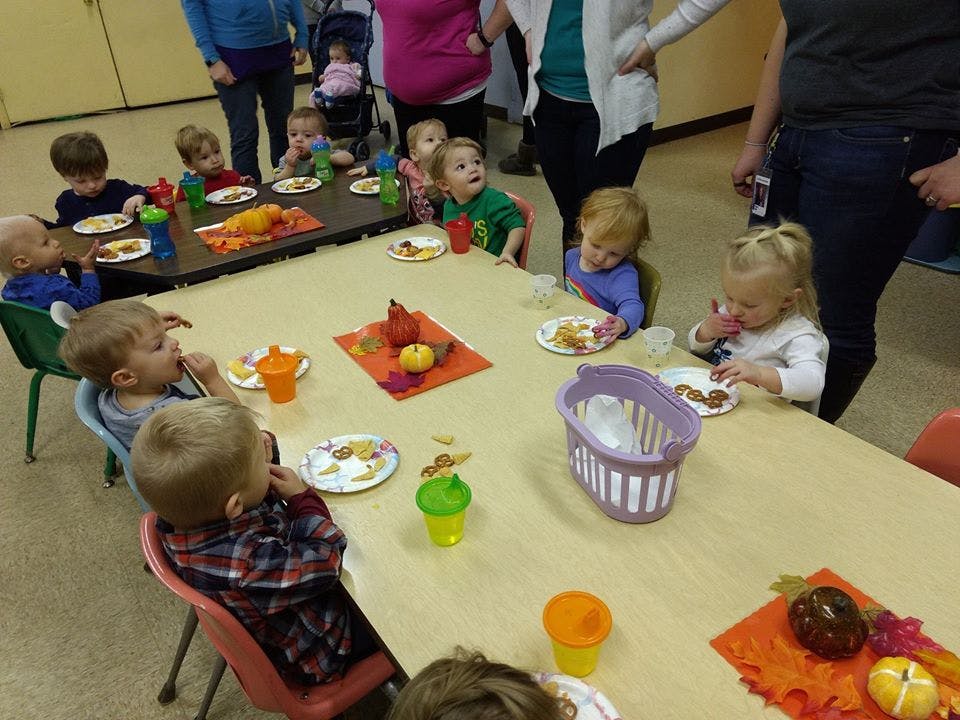 Children sitting at tables with plates and cups