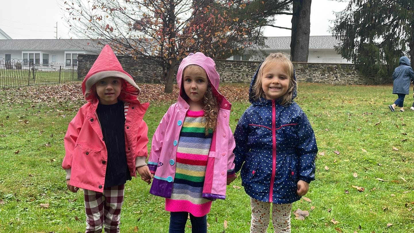Three children in raincoats standing outdoors
