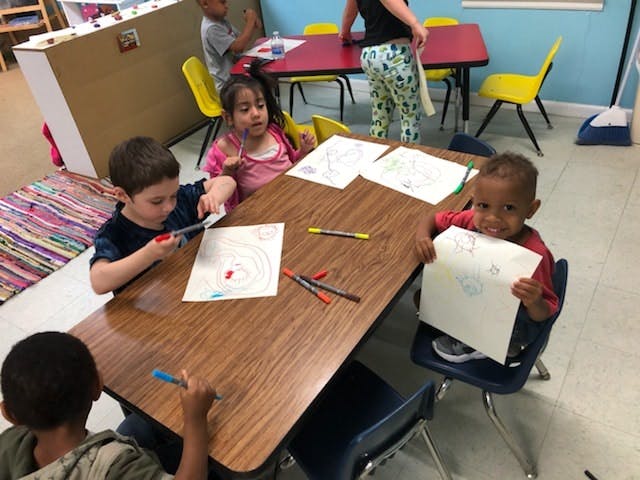 Children drawing at a table in a classroom