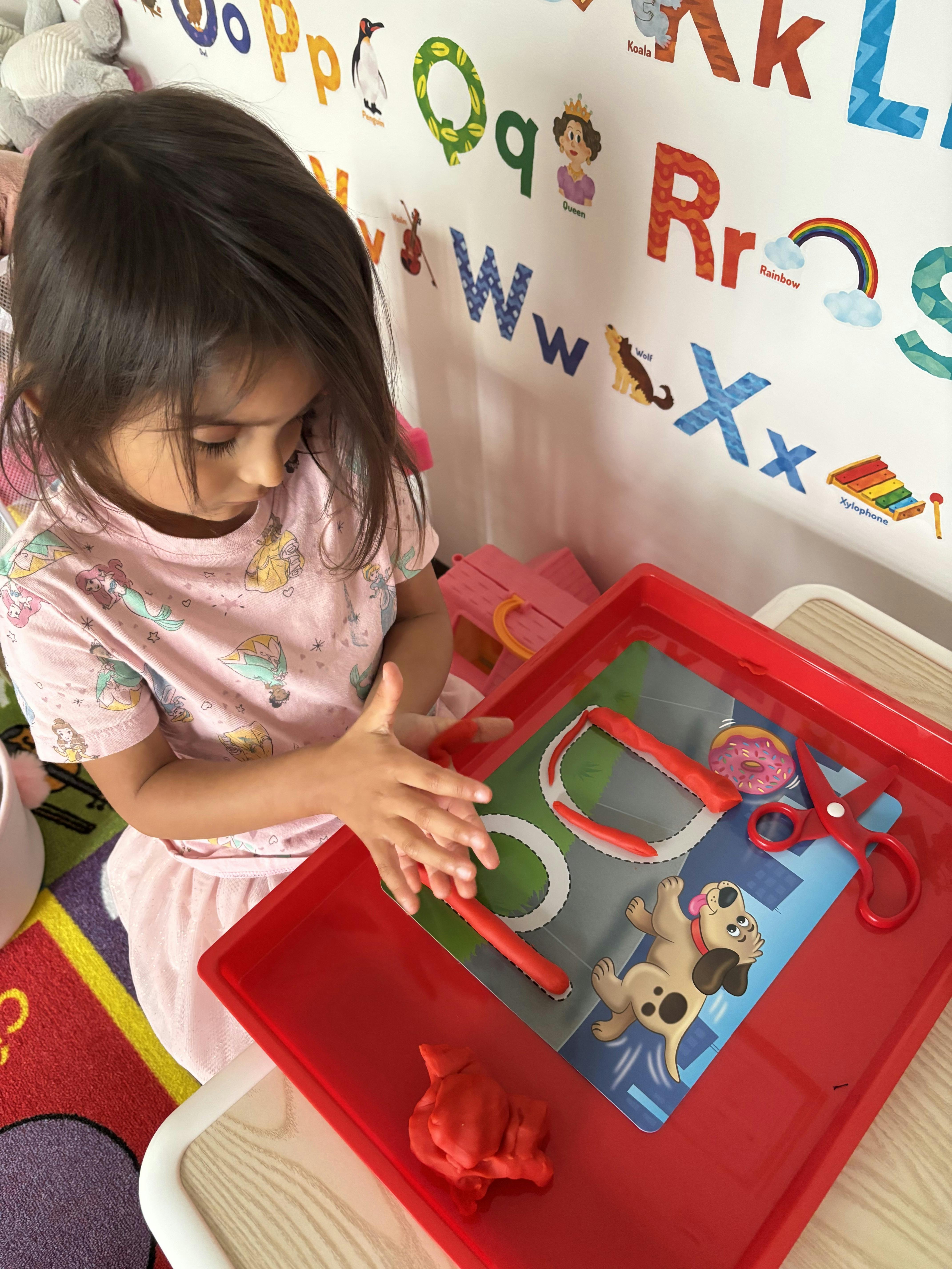 Child playing with red tray of toys and tools